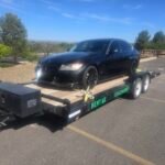 Black BMW on Monsoon Trailer Rental LLC flatbed trailer, ready for transport.