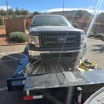 Gray Ford F-150 truck loaded onto a flatbed trailer for transport.
