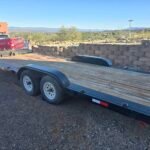 Monsoon Trailer Rental - Red pickup truck towing a heavy duty wood deck equipment trailer in a residential area.